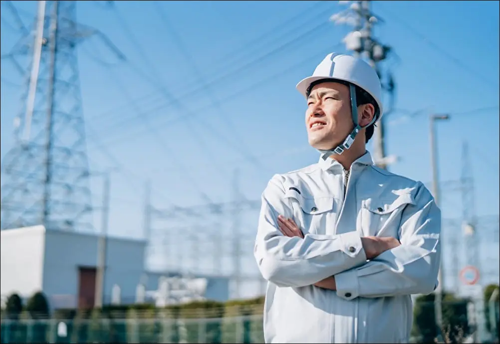 変電設備の前に立つ電気技術者のイメージ